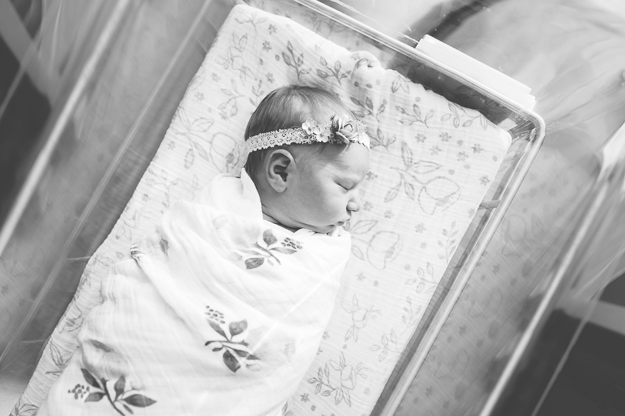 black and white image of newborn baby sleeping in bassinet at hospital