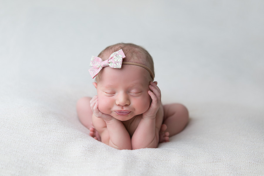 newborn girl frog pose with pink bow