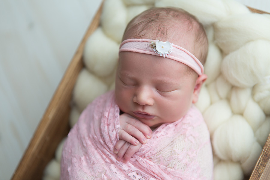 newborn girl with pink headband sleeping swaddled