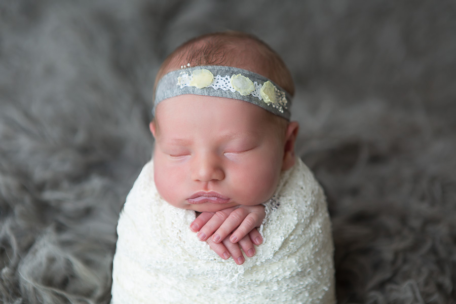 newborn baby girl with grey headband sleeping