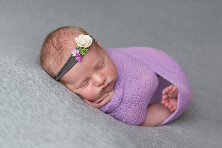 7 day old baby girl in purple swaddle