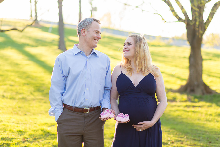 parents to be holding two sets of pink shoes