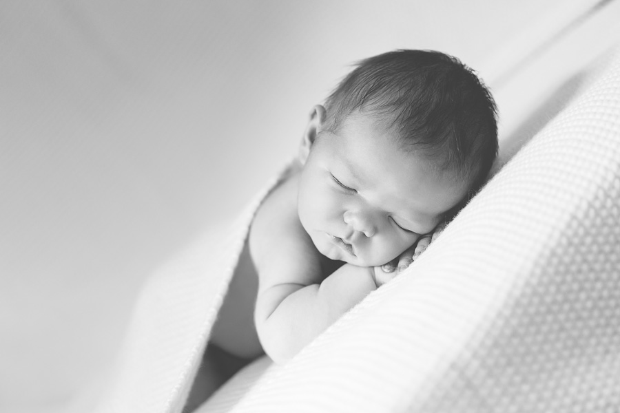 newborn boy sleeping on white blanket