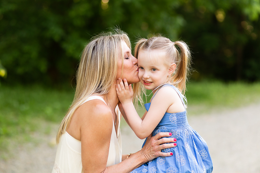 mom kissing five year old daughter on the cheek